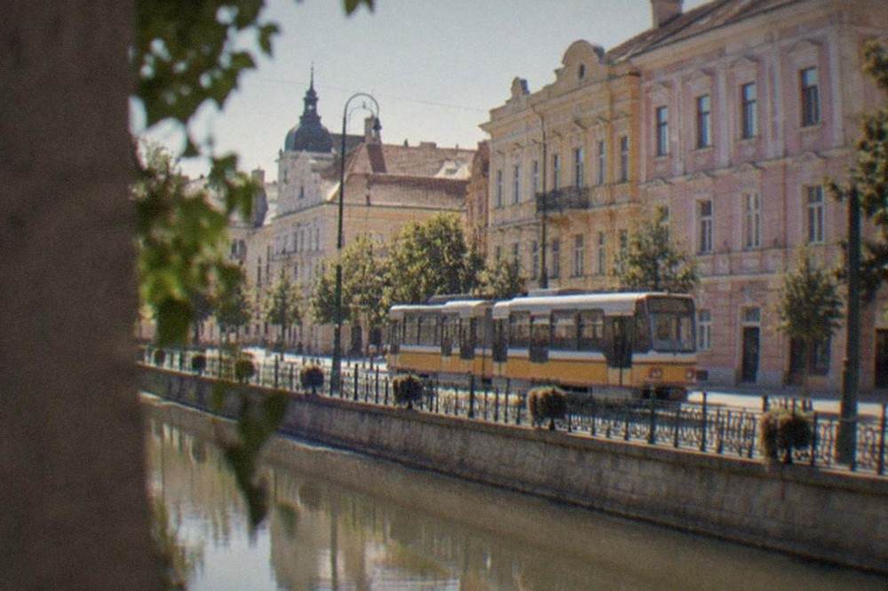 A tram moving along a street in central Timisoara past pastel-colored Secession-style buildings