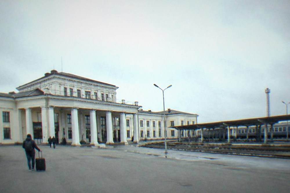 A passenger checking a departure board inside a Romanian railway station concourse