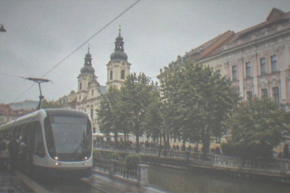 A modern Timisoara tram at a stop with passengers boarding near the station area