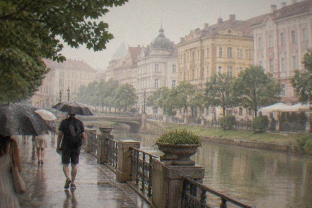 Umbrellas crossing a Timisoara square during light summer rain