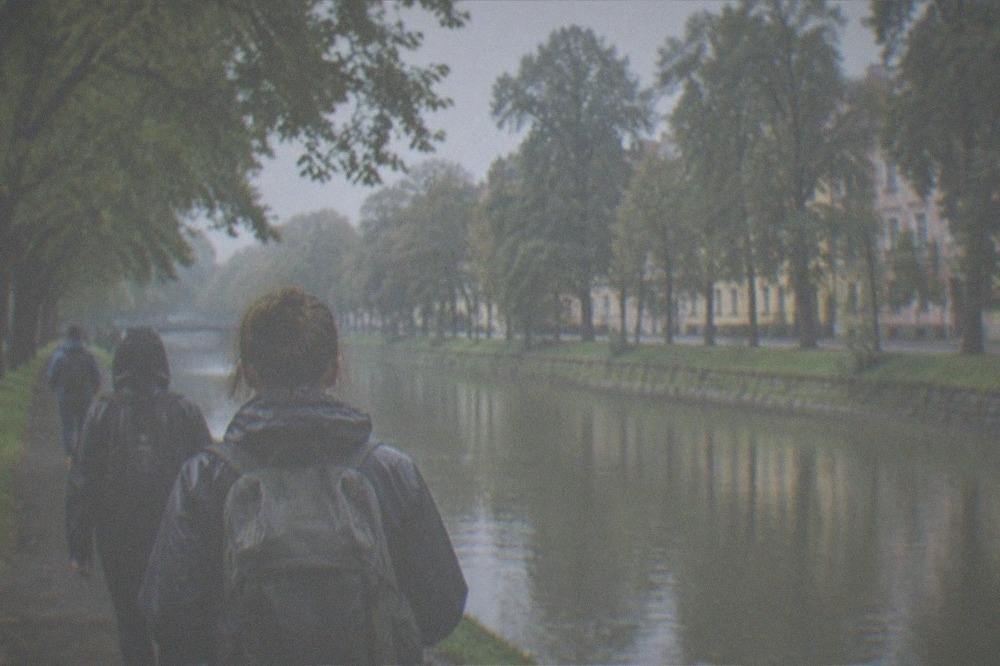 Travelers with backpacks and layered clothing walking beside the Bega canal