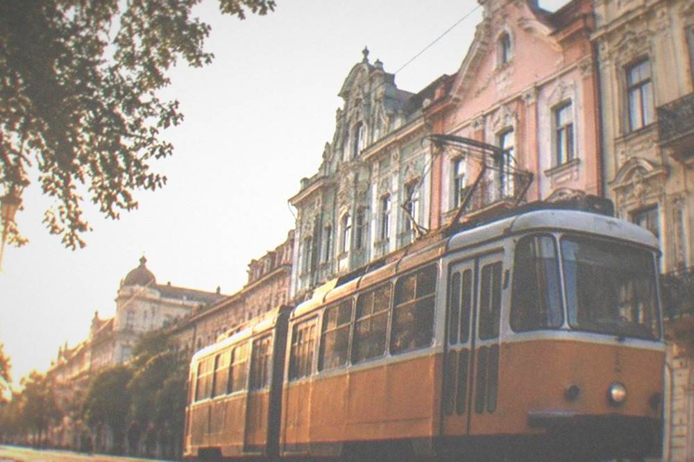 A tram passing colorful buildings on a city street