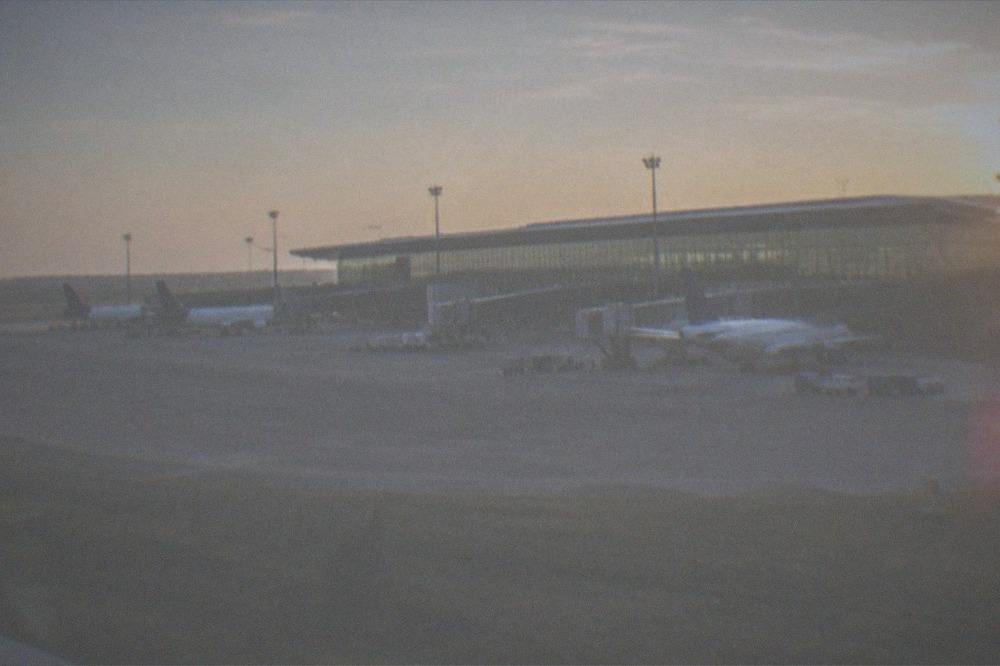A modern airport terminal exterior with planes at gates
