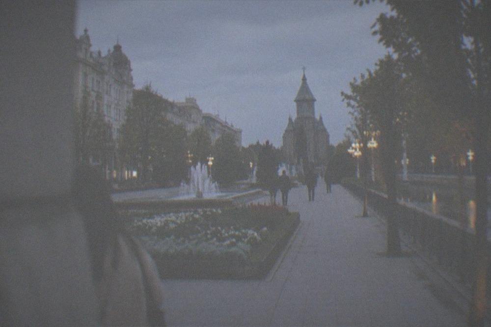 An evening promenade along a canal with lit trees and people strolling