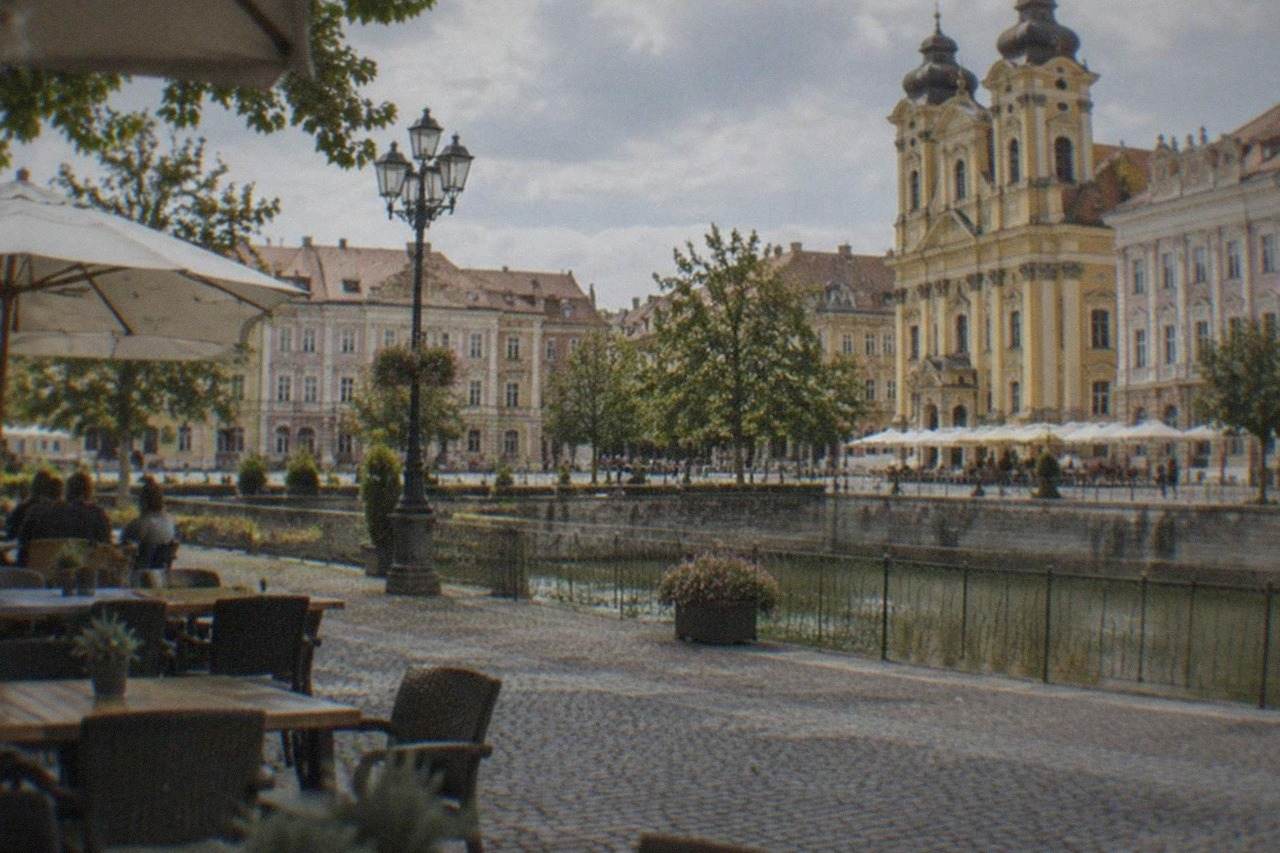 Colorful baroque buildings and cafe tables around a large square in Timisoara