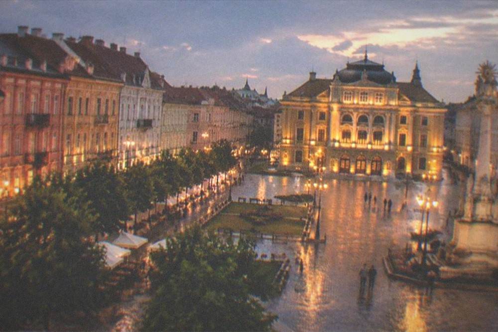 Evening view of an illuminated square with the opera building and lit facades