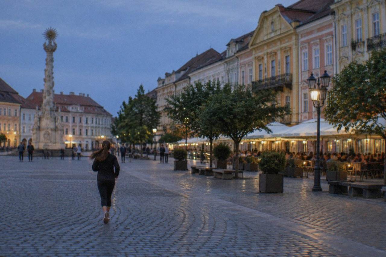 Union Square in Timisoara at dusk with colorful baroque facades and outdoor cafe tables