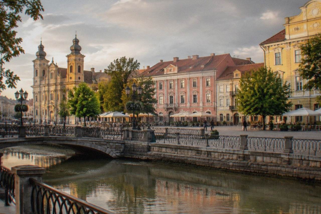 Colorful baroque buildings around a square in Timisoara at golden hour