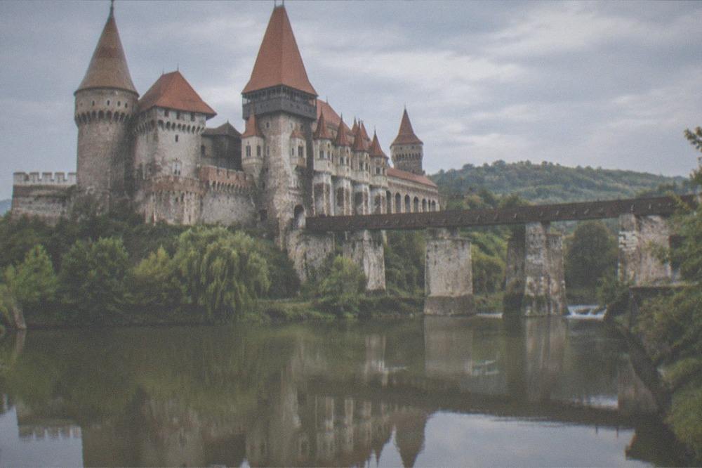 Corvin Castle's towers and bridge reflected in water at Hunedoara